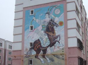 Mural of a man brandishing a bow on horseback viewed on the end of a tenement block in Barkul/Balikun in Xinjiang province, China.