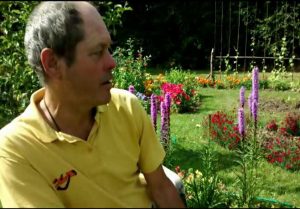 Profile of middle-aged caucasian male in a sunny garden with flowers blooming